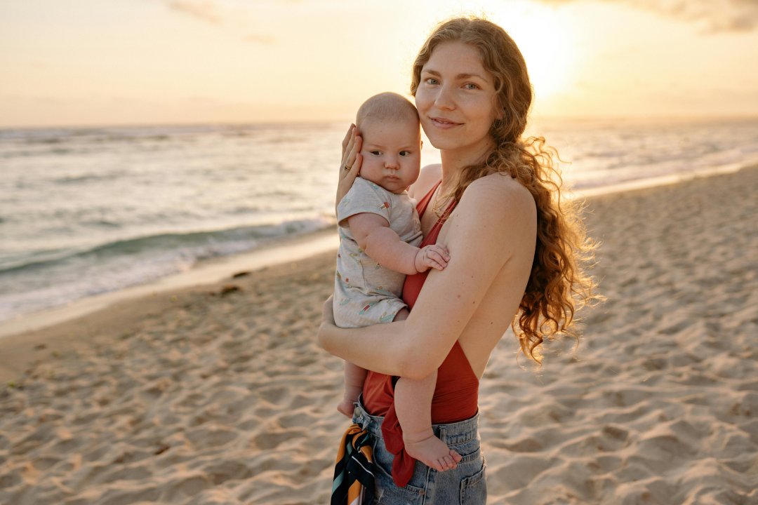 A woman cradles a baby on the beach